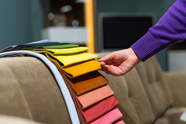 The woman chooses the fabric on the sofa A women looks at tissue samples Selects the color of the sofa Textile industry background Tissue catalog