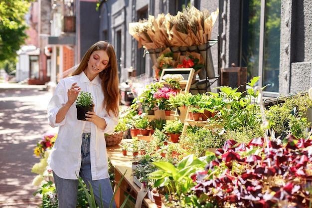 Woman chooses a flower in a pot in the market outside