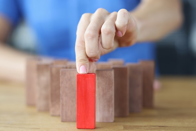 Photo woman chooses red wooden block among others on wooden table making right decision concept