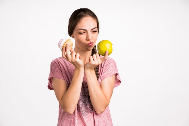 Woman choosing between apple and cupcake