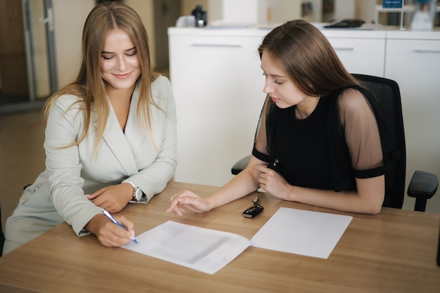 Woman choosing and buying car at car showroom car salesman helps them to make right decision female