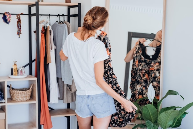 Photo woman choosing clothes on clothes rack dressing looking herself in mirror