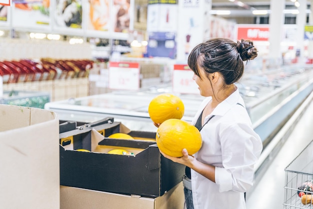 Woman choosing melons in grocery store