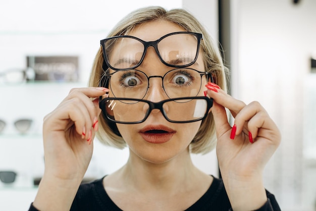 Photo woman choosing a pair of eyeglasses at optics store