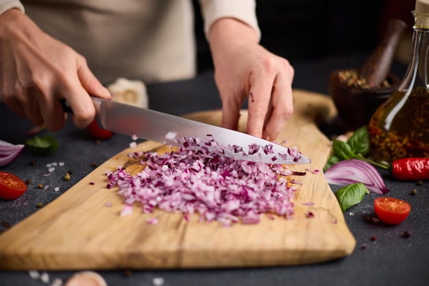 Photo woman chopping red mars onion on wooden cutting board at domestic kitchen