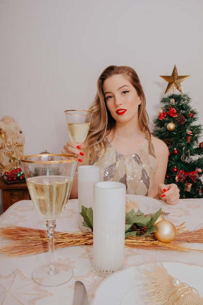 Woman at christmas dinner with sparkling wine and gifts