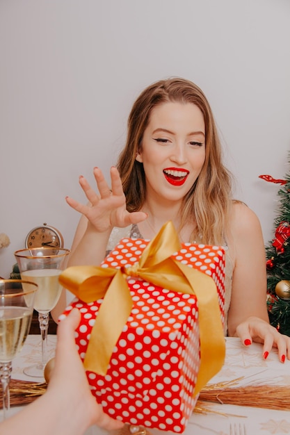 Woman at christmas dinner with sparkling wine and gifts