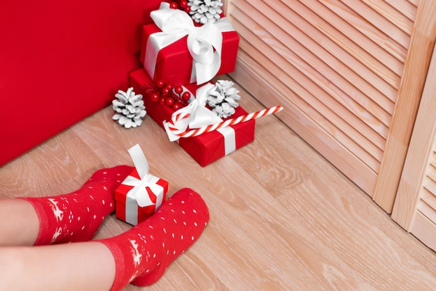 Woman in Christmas socks at home. Holds a gift for the New Year. Nice background. Woman resting at home for Christmas