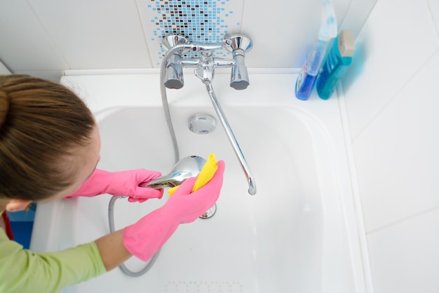 A woman cleaning bath at home Female washing bathtub and faucet