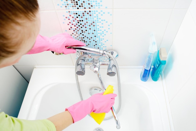 A woman cleaning bath at home Female washing bathtub and faucet