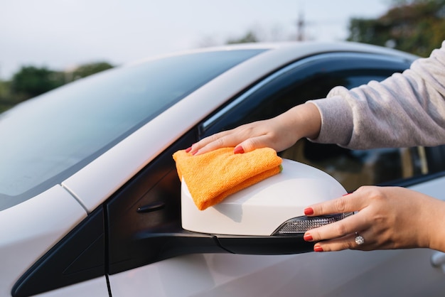 A woman cleaning car with microfiber cloth, car detailing (or valeting) concept