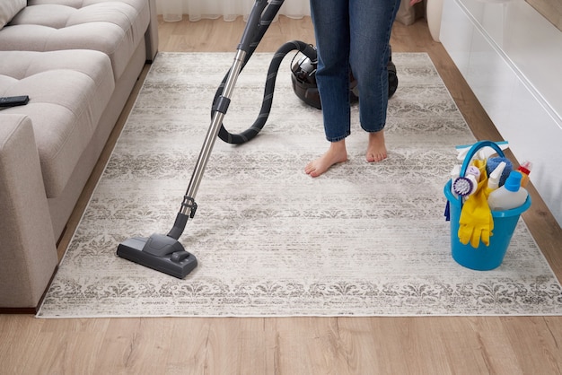 Woman cleaning the carpet with vacuum cleaner in the living room