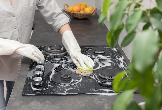 Woman cleaning gas stove in kitchen at home Housekeeping and clean house concept