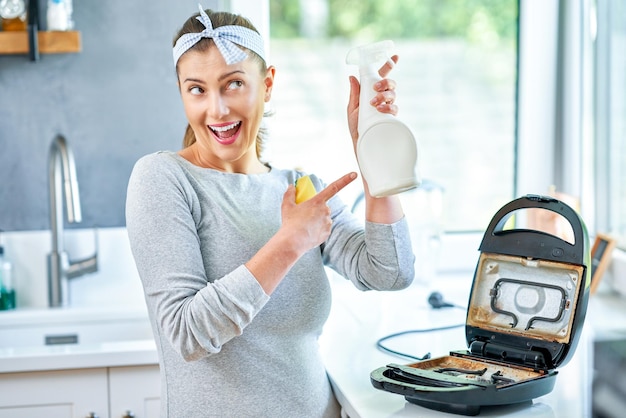 Woman cleaning grill or toaster machine in the kitchen