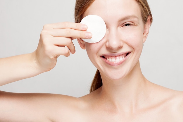 Woman cleaning her face with cotton pads