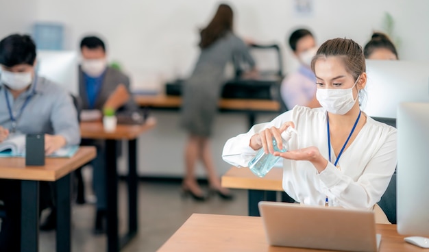 Woman cleaning her hands at the office. Sick with mask for coronavirus.