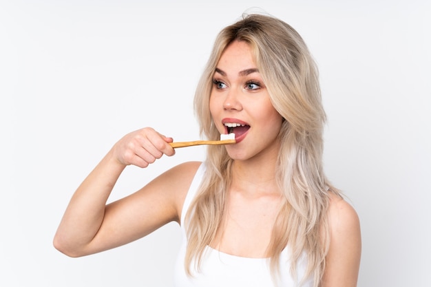 Woman cleaning her teeth over isolated wall