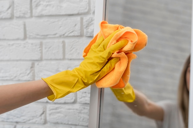 Woman cleaning mirror with cloth