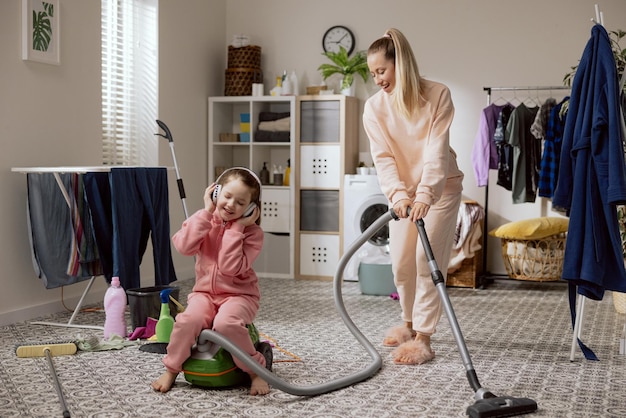 Woman cleans bathroom laundry room vacuums floor with vacuum cleaner on equipment