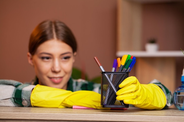 Woman cleans office in the yellow gloves wipes the dust off the office desk