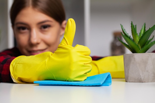 Woman cleans office in the yellow gloves wipes the dust off the office desk