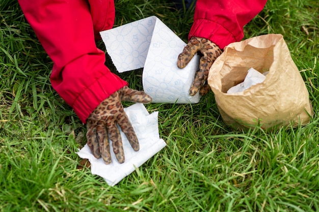 A woman cleans up dog poop on the lawn in the yard of the house Closeup Roll of toilet paper and excrement on the grass Territory cleaning