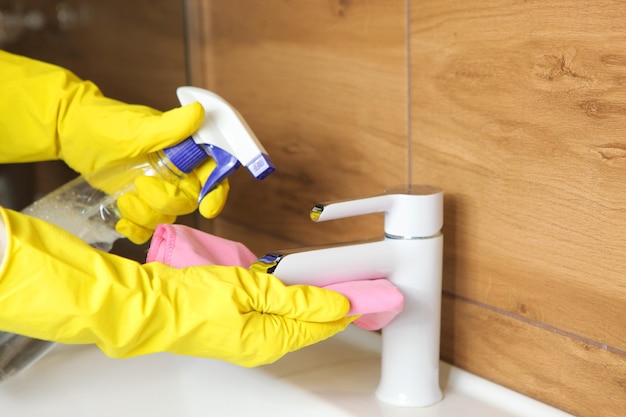 Woman cleans up the sink and faucet in the bathroom cleaning and disinfection