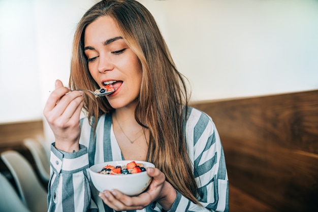 Woman close up eating oat and fruits bowl for breakfast