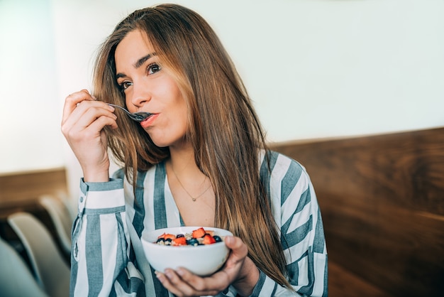 Woman close up eating oat and fruits bowl for breakfast