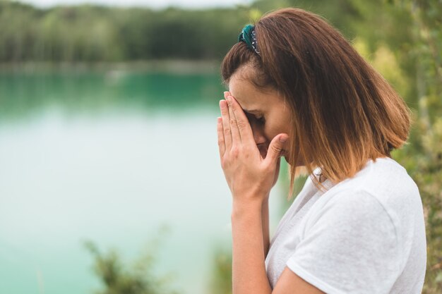 Woman closed her eyes, praying in outdoors. Hands folded in prayer concept for faith, spirituality and religion