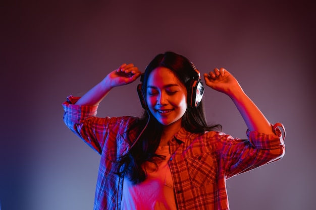 A woman closes her eyes while listening to music wearing headphones dancing