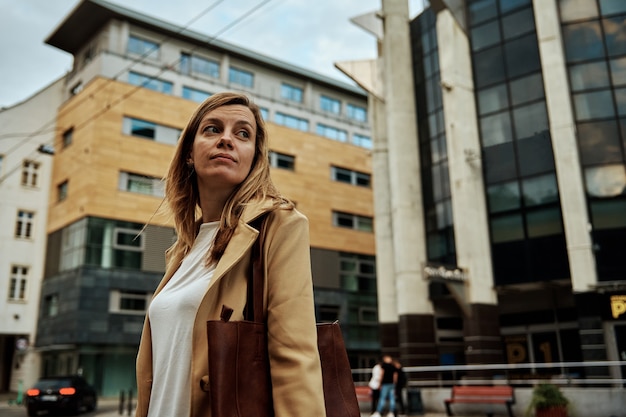 Woman in coat walks at city street