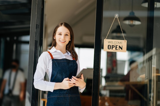 Woman coffee shop owner holding notepad and digital tablet ready to receive orders in cafe restaurant woman barista cafe xA