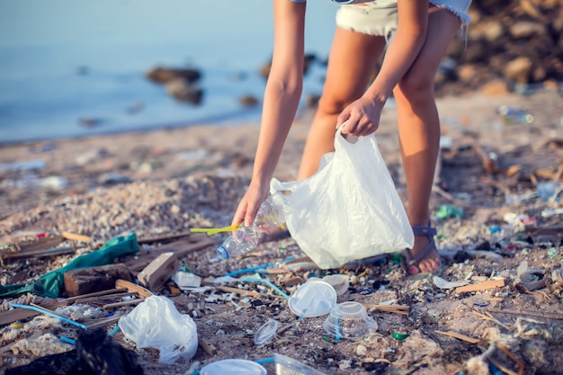 Woman collect garbage on the beach. Environmental protection concept