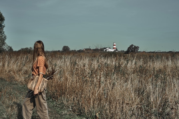 The woman collects flowers in the field. Biodegradable bag.