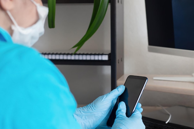 A woman at a computer in a protective face mask and protective gloves receives calls Medicine