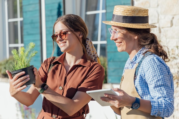 A woman consults a female gardener about plants before buying them in a garden center