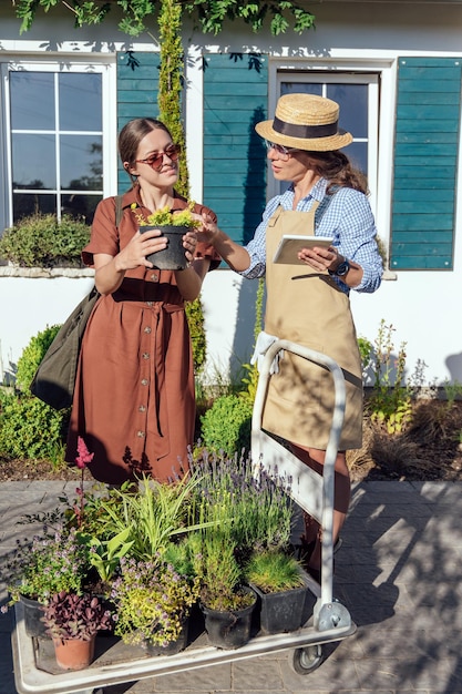 A woman consults a female gardener about plants before buying them in a garden center