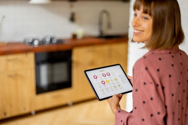 Woman controls home devices with a digital tablet at home