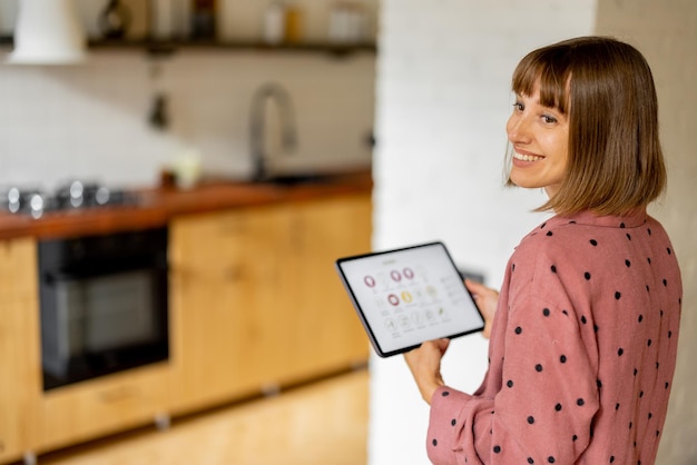 Woman controls home devices with a digital tablet at home