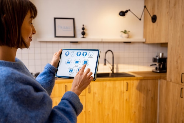 Woman controls kitchen appliances with a digital tablet