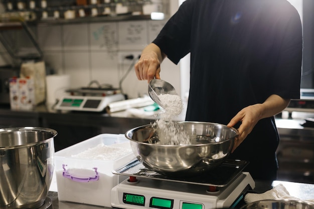 A woman cook works in a modern industrial kitchen The process of making cakes in a bakery or cafe