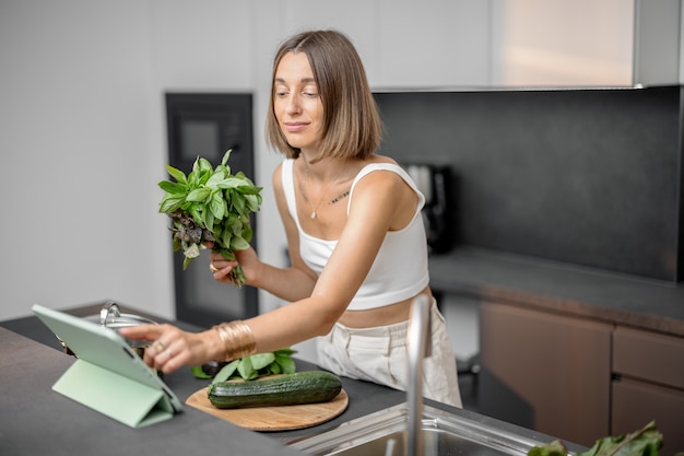 Woman cooking with fresh vegetables and greens in the sink