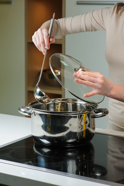 Woman cooks the soup in the kitchen