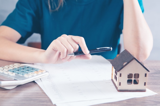 woman counts on a calculator in front of the house