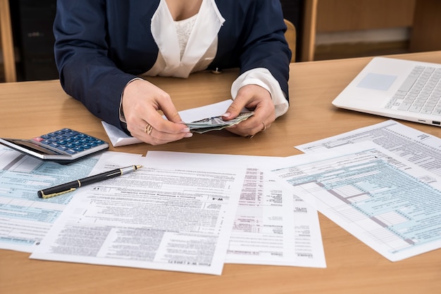 Woman counts money by filling in tax forms