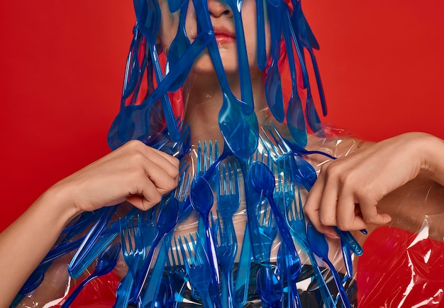 Woman covering her face and body with blue plastic tableware