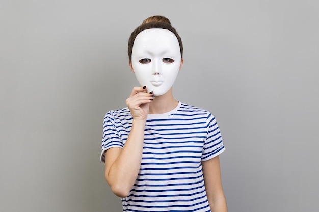 Woman covering her face with white mask hiding personality conspiracy and privacy