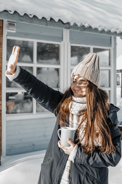 Woman covers herself from the sun with her hand outdoors during winter near a house