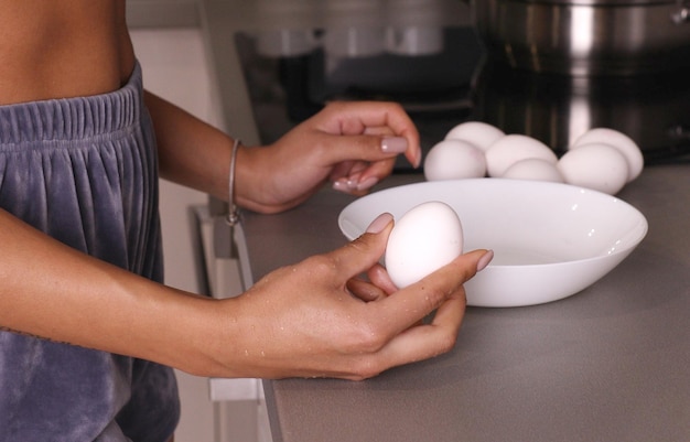 Woman cracking eggs into glass bowl.